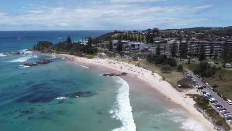 vista aérea de una hermosa playa de arena con una ciudad de playa en el fondo