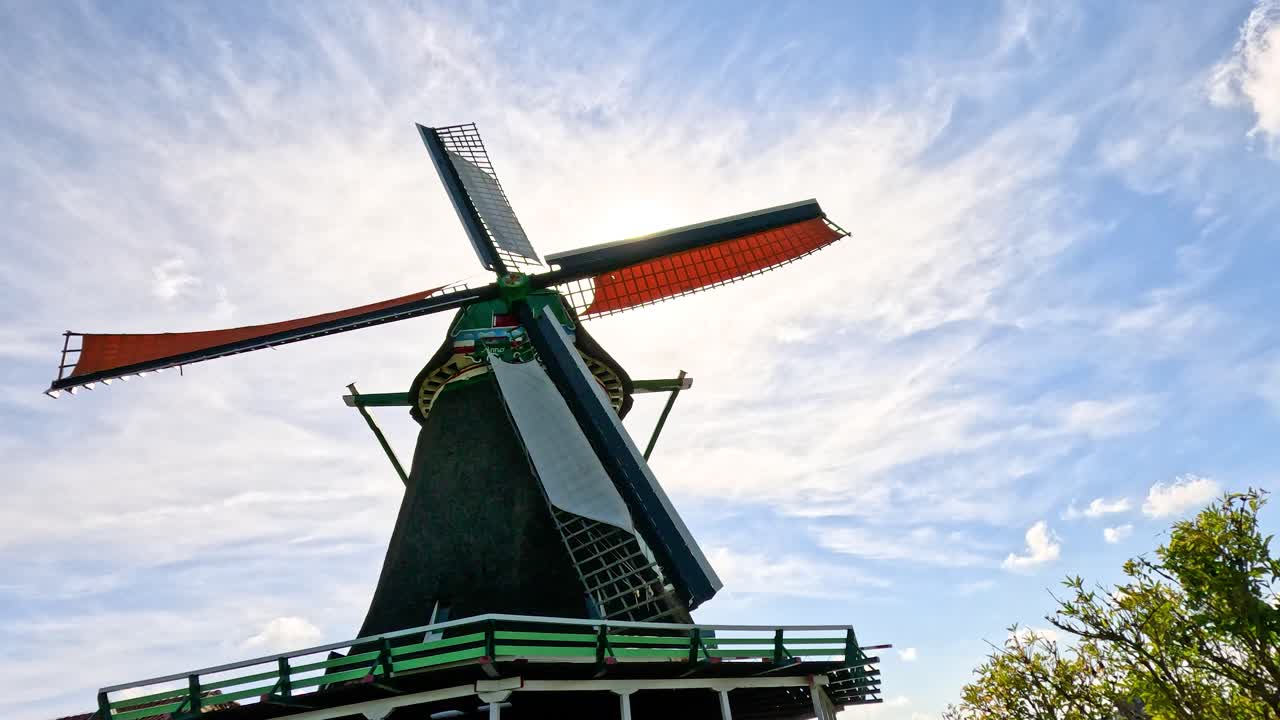 Historic windmill blades turning in sunlight, low angle, vibrant blue sky, Zaandam, Netherlands