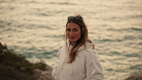 Bohemian-attractive-Spanish-female-smiling-shyly-by-the-sea-at-sunset