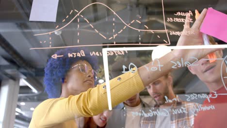 Happy diverse creative colleagues brainstorming making notes on glass wall in office, slow motion