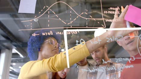 happy diverse creative colleagues brainstorming making notes on glass wall in office, slow motion