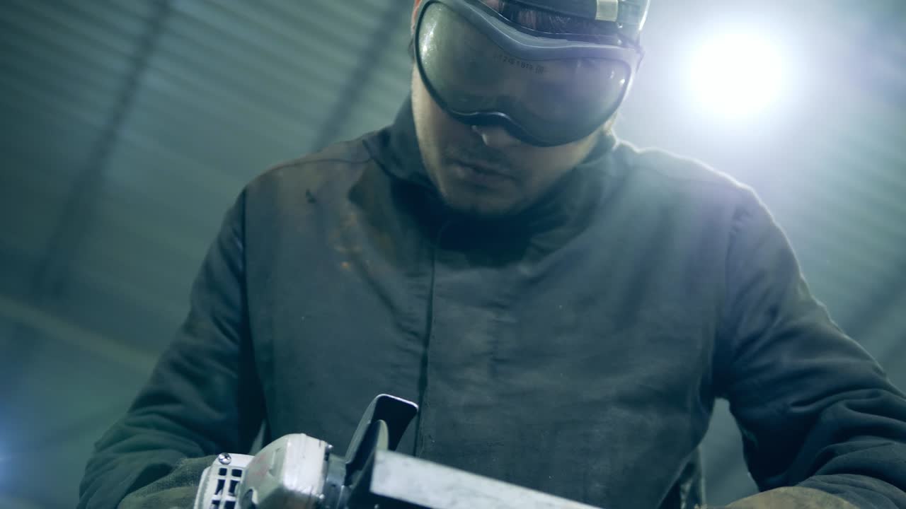 el soldador está usando una sierra rotativa para cortar una viga metálica