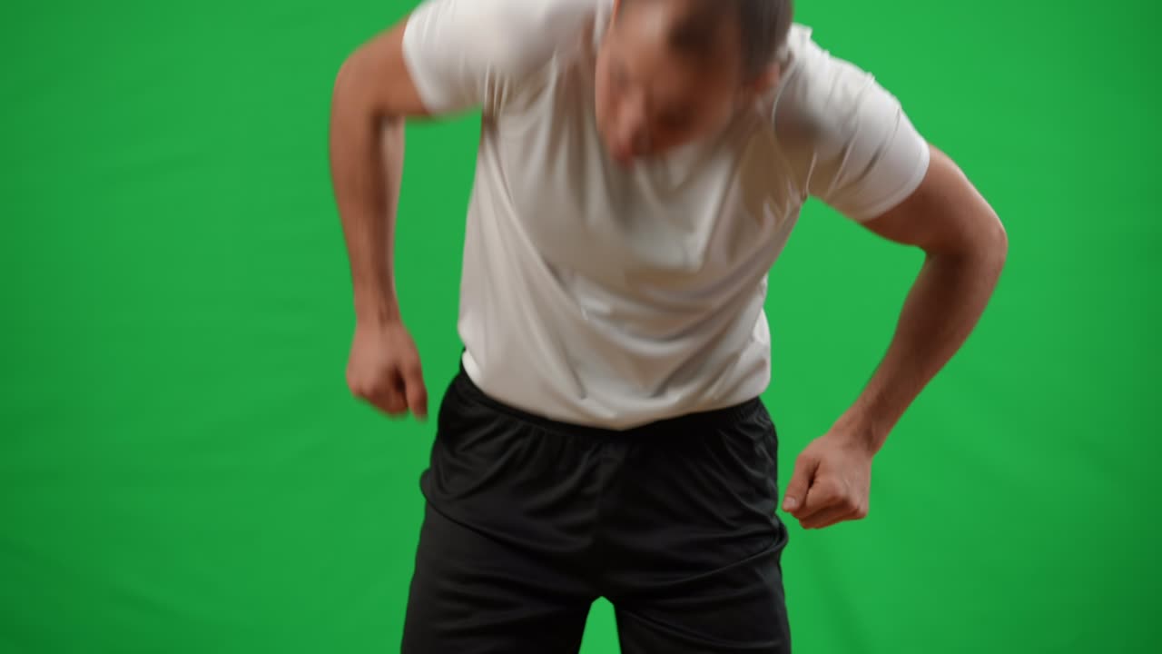 joven caucásico haciendo malabarismos con la pelota de fútbol en la espalda en cámara lenta atrapando con las manos. joven deportista profesional entrenando en chromakey maqueta de fondo de pantalla verde.