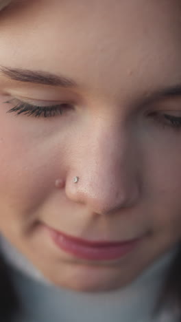 close-up of white woman with pink lips and small nose ring, eyes closed, focused and calm expression, showing natural beauty with soft lighting and gentle features