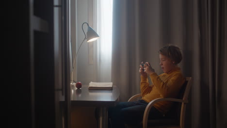 boy playing on phone at desk