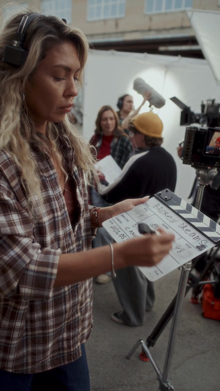 Female Film Crew Member Writing Information on Clapperboard on Movie Set