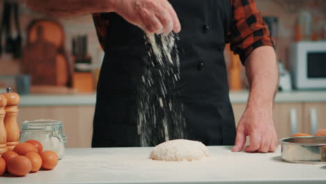 man sifting flour on dough