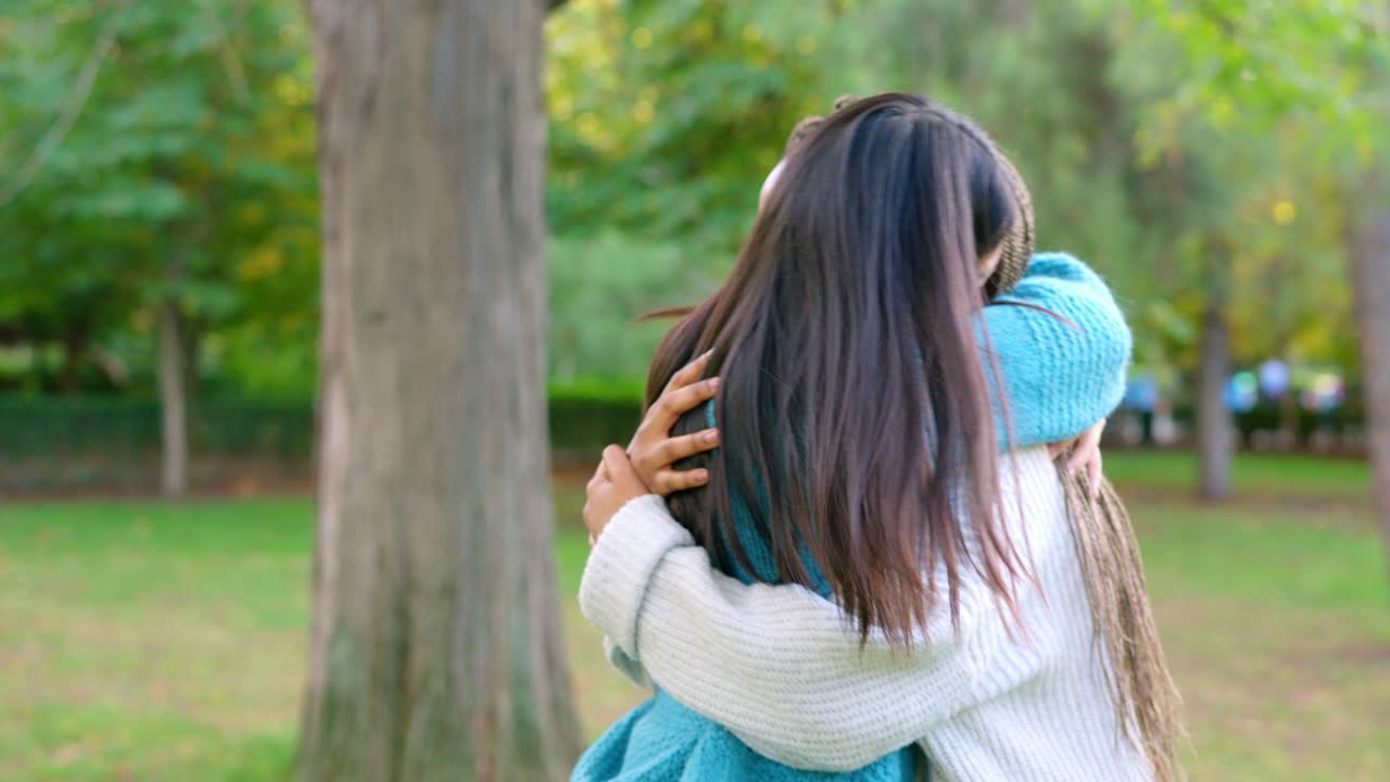 Two diverse women sharing a warm hug in a park