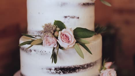 close up of layered wedding cake with white frosting and pink rose decor 1080p 60fps