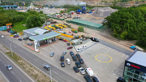 helipad near the car dealership building. helicopter landing near the car line to the gas station. construction site at backdrop. aerial view.