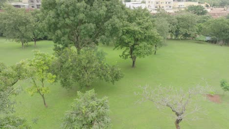 AERIAL---public-park-under-a-cloudy-sky,-Abuja,-Nigeria,-forward-tilt-up-reveal