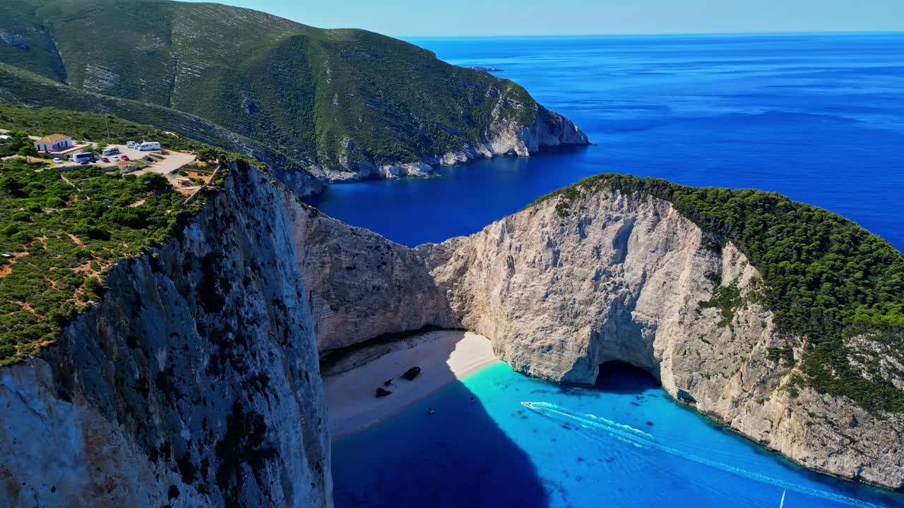 panorámica aérea de drones disparada sobre barcos a lo largo de la laguna que rodea la icónica playa del naufragio o la playa de navagio en grecia en un día soleado