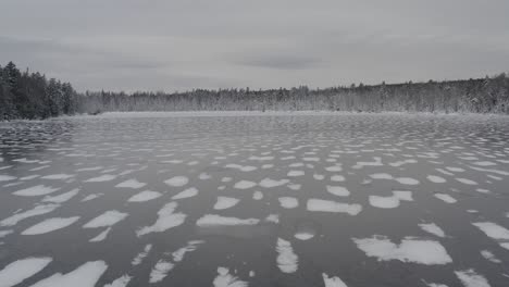 Vuelo-Aéreo-Sobre-Un-Lago-Congelado-Con-Nevadas-Frescas-Rodeado-De-Silvicultura