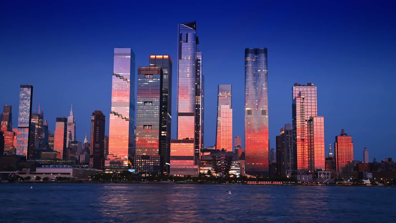Hudson Yards skyscrapers reflecting sunset in New York. The glass skyscrapers of Hudson Yards glow with sunset reflections above the Hudson River in New York City