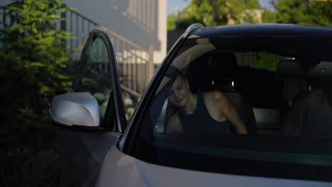 Happy-brunette-girl-gets-into-the-car-with-her-boyfriend-wearing-sunglasses-and-fastening-her-seat-belt-before-starting-to-drive-in-the-car