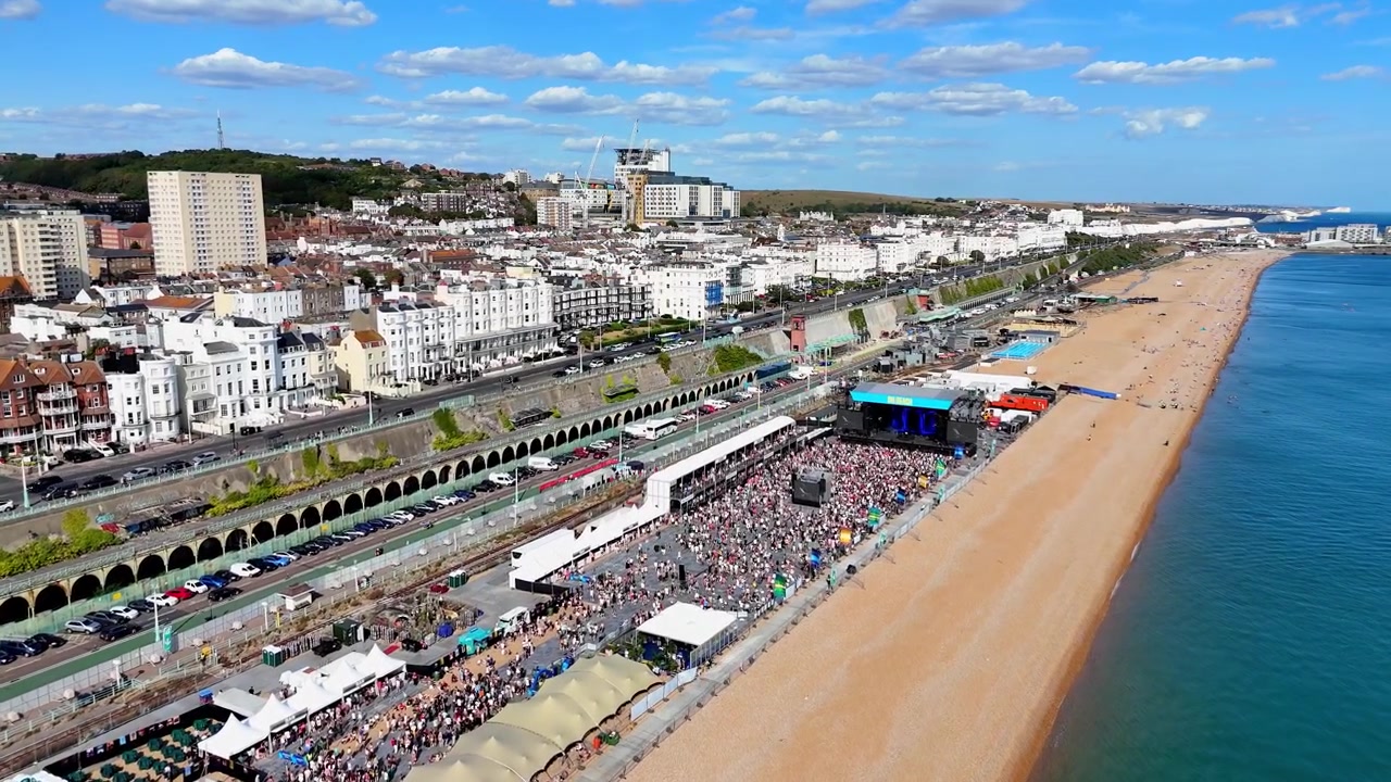 Il vivace lungomare estivo di Brighton, che cattura folle di festival, barche al largo, spiagge affollate e un vivace turismo balneare. Approccio aereo dal mare alla spiaggia.