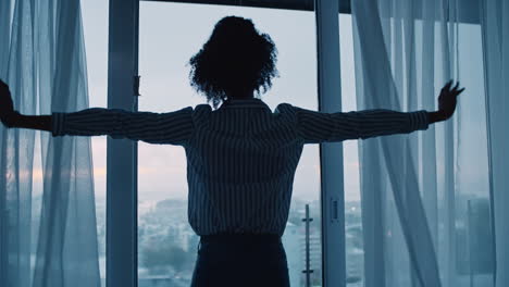 business woman opening curtains in hotel room looking out window at fresh new day successful independent female planning ahead on cloudy morning