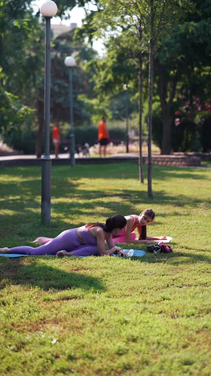 dos mujeres practicando yoga en un parque