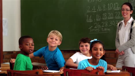 Teacher-and-young-pupils-smiling-at-camera-in-classroom