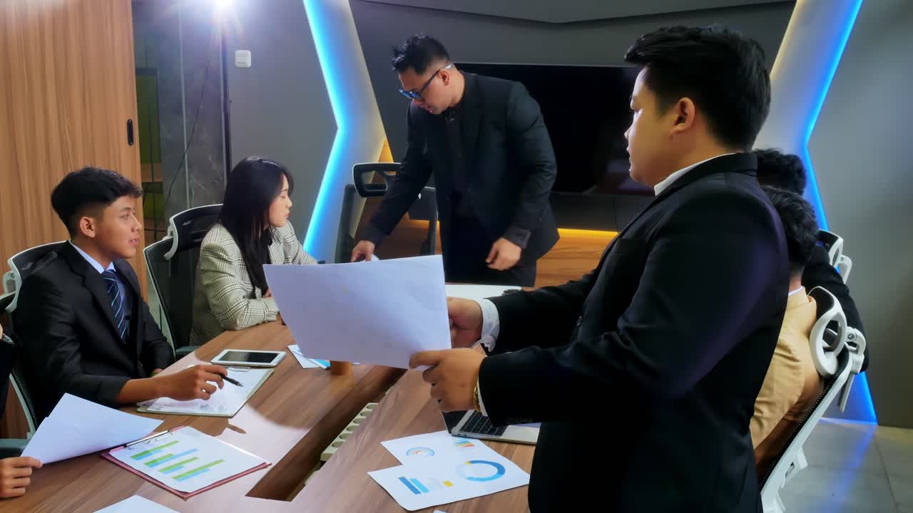 Confident business team collaborates discussing reports and charts in modern meeting room