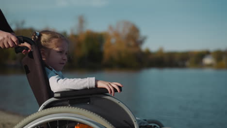 cute girl with disability looks at flow of water in river