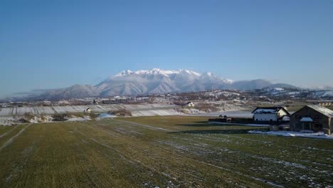 vistas panorámicas a las montañas cubiertas de nieve desde los campos rurales en rumania durante el invierno tardío