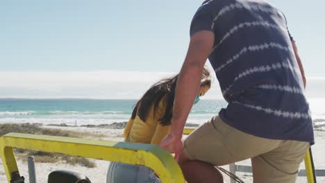 happy caucasian couple sitting in beach buggy by the sea talking