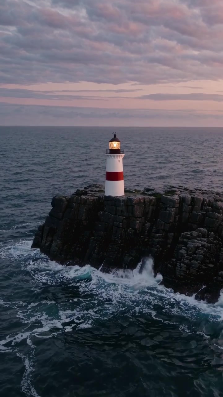 Vista aerea di un faro su uno sperone roccioso al crepuscolo.
