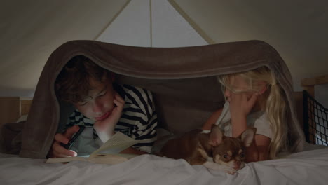 children reading in bed with their dog at night