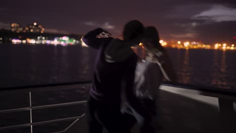 silhouette of two beautiful young women dancing on ship deck at night. girlfriends on the boat