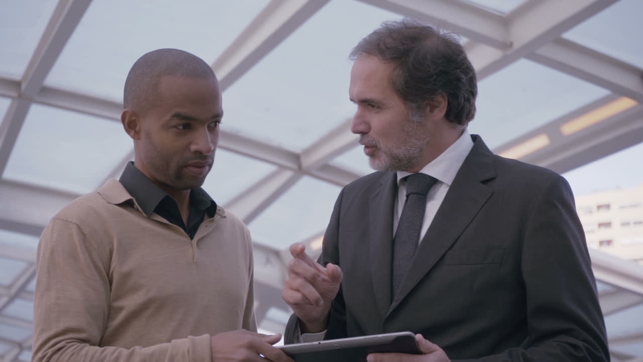 Concentrated businessmen discussing projeсt with tablet