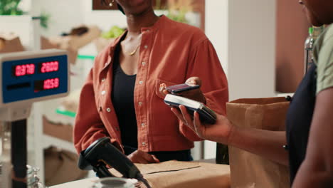 woman using mobile nfc payment to pay for bio produce