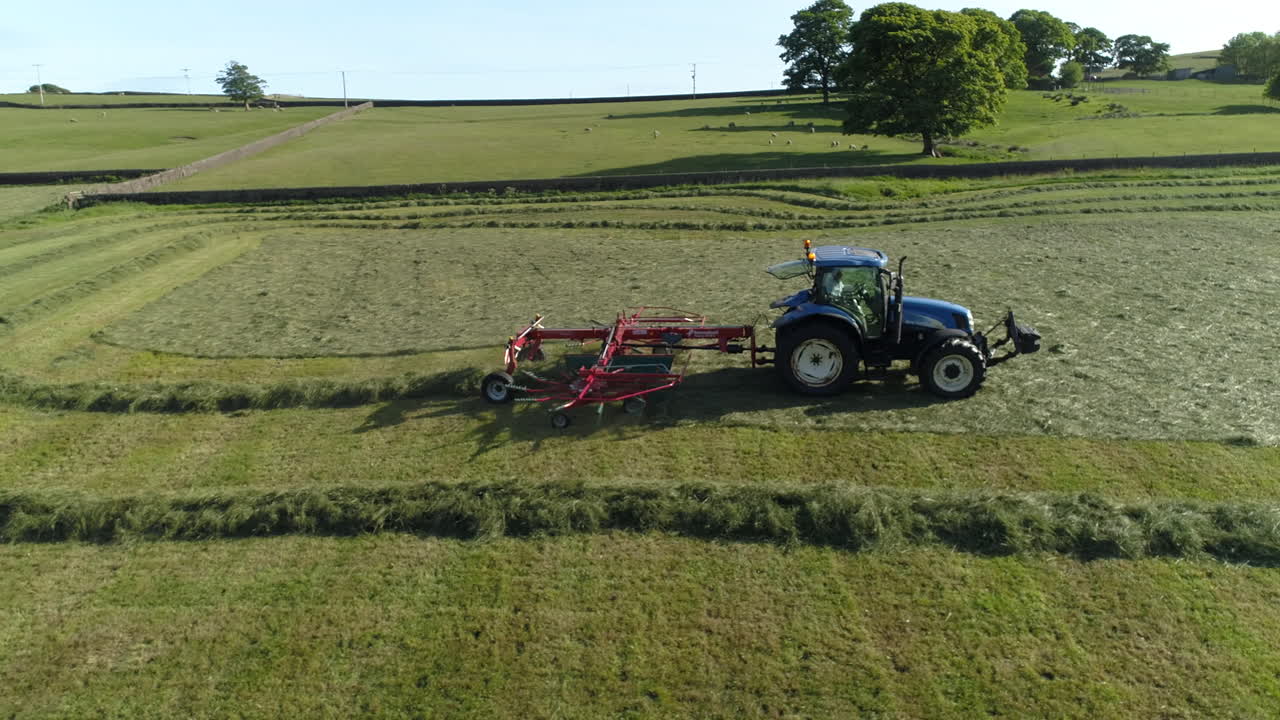 Drone shot, of a farmer working his land in a tractor, shot from the side view, on a West Yorkshire farm