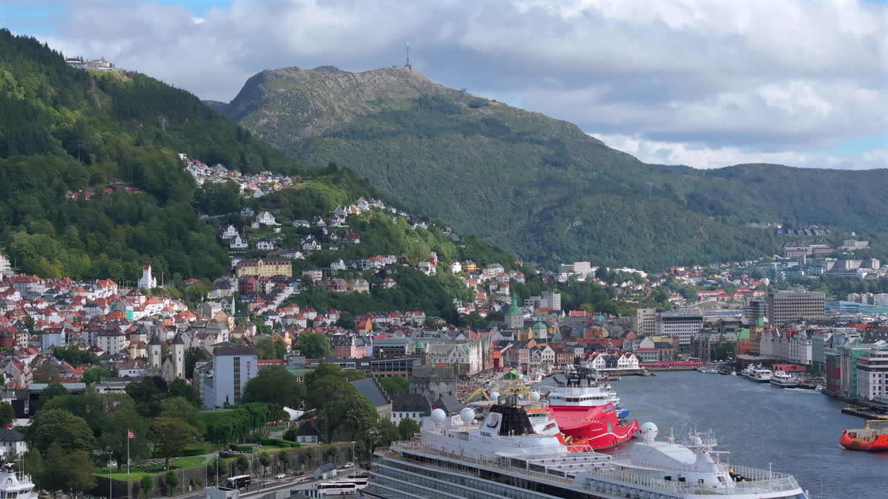 Aerial view of Bergen city center with Mount Fløyen and green hills in the background on a clear summer afternoon