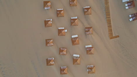 Sun umbrellas beach chairs on tropical resort. Aerial top view parasols loungers