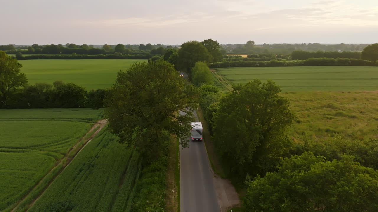 Drone tracking a camper van through a alley road in rural Germany, golden hour