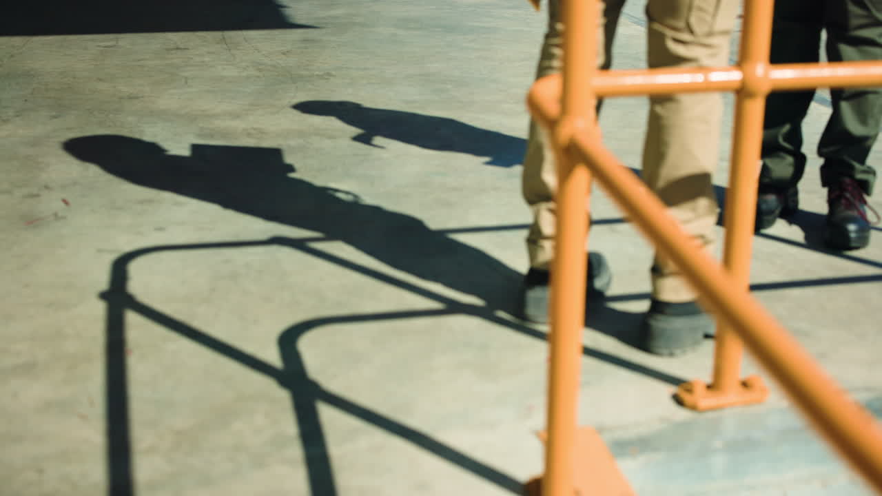 Two People's Legs and Shadows on Sunny Concrete Ground