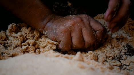 close up of hand kneading tight dough in a wooden plate