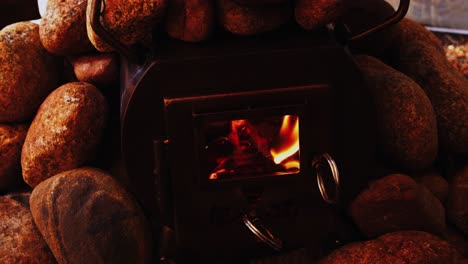 orange flames blaze in cozy wood stove surrounded by hot rocks