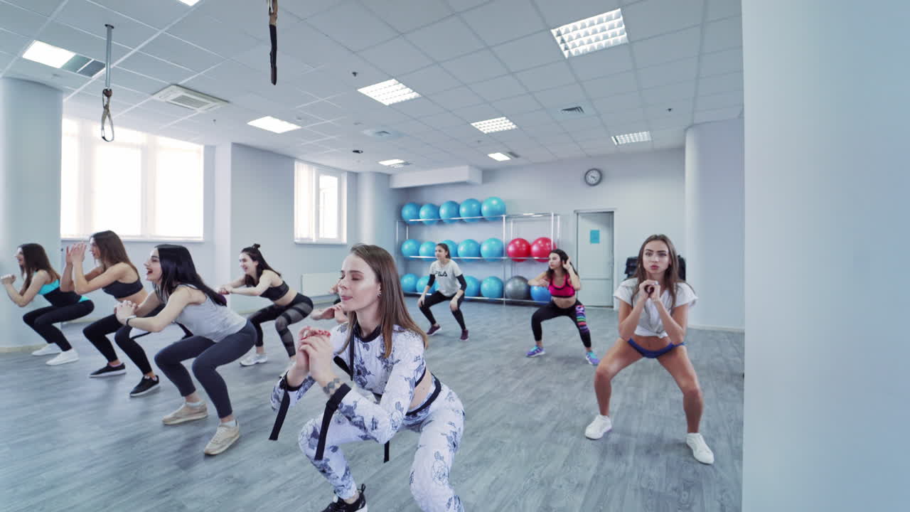 Group of sportive people in gym training. View of young women exercising in aerobics class