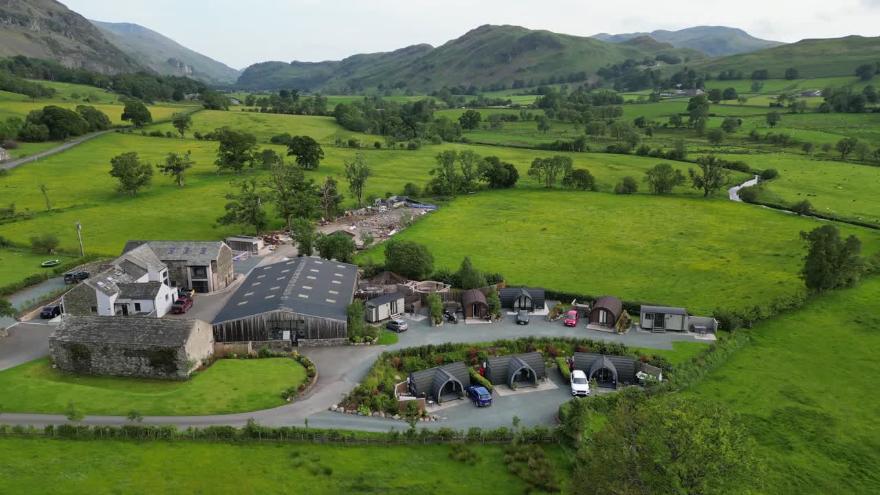 Drone spin over Mire House and lush green hills in Lake District, UK