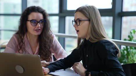 two ladies in office sit in front of laptop and discuss strategies. business conversation of two female colleagues. business ladies close up.