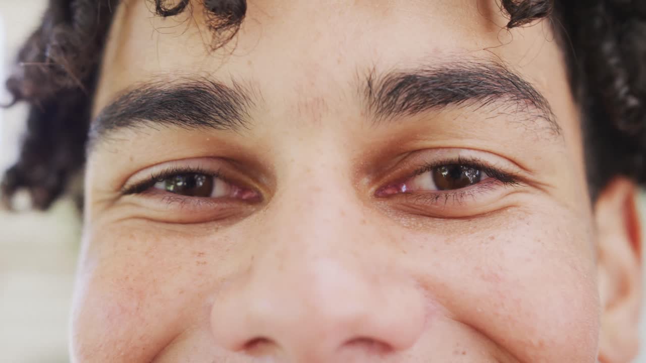 retrato de un hombre biracial feliz pasando tiempo en casa y mirando a la cámara