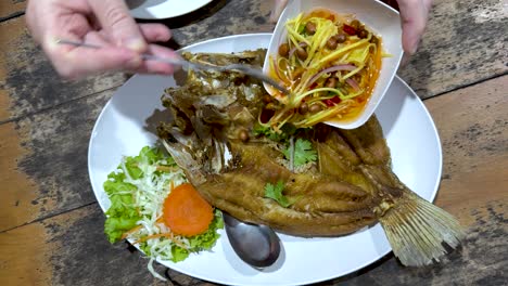 vertiendo salsa sobre un plato de pescado frito