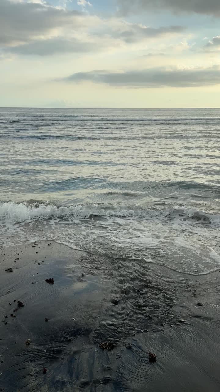 Onde marine che lambiscono dolcemente una spiaggia di sabbia scura