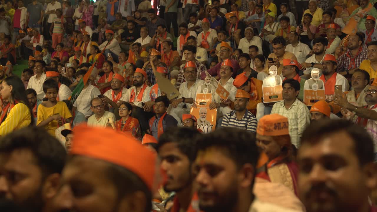 Crowd of Indian men and women voters with BJP merchandise gathered at Assi ghat to attend Chief Minister Yogi Adityanath Lok Sabha election campaign rally