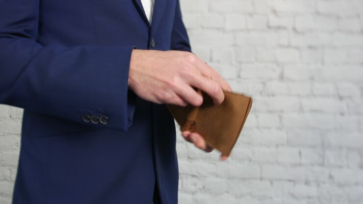 An empty wallet being opened by a business man showing that he has no money
