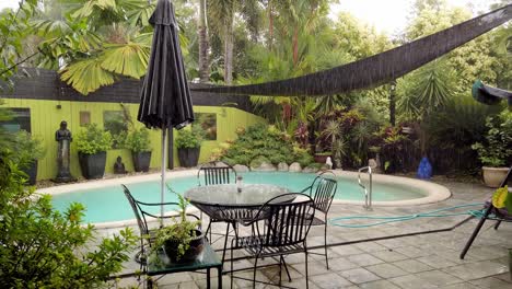 a beautiful outdoor pool surrounded by lush, green plant life in queensland, australia on a heavy rainy day - wide shot