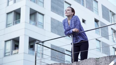 Serious-businesswoman-leaning-on-railing