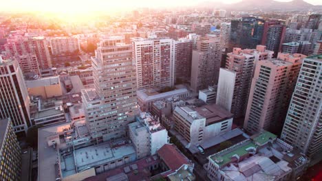 Aerial-view-looking-down-over-downtown-Santiago-business-district-with-colourful-glowing-orange-sunset-cityscape-skyline